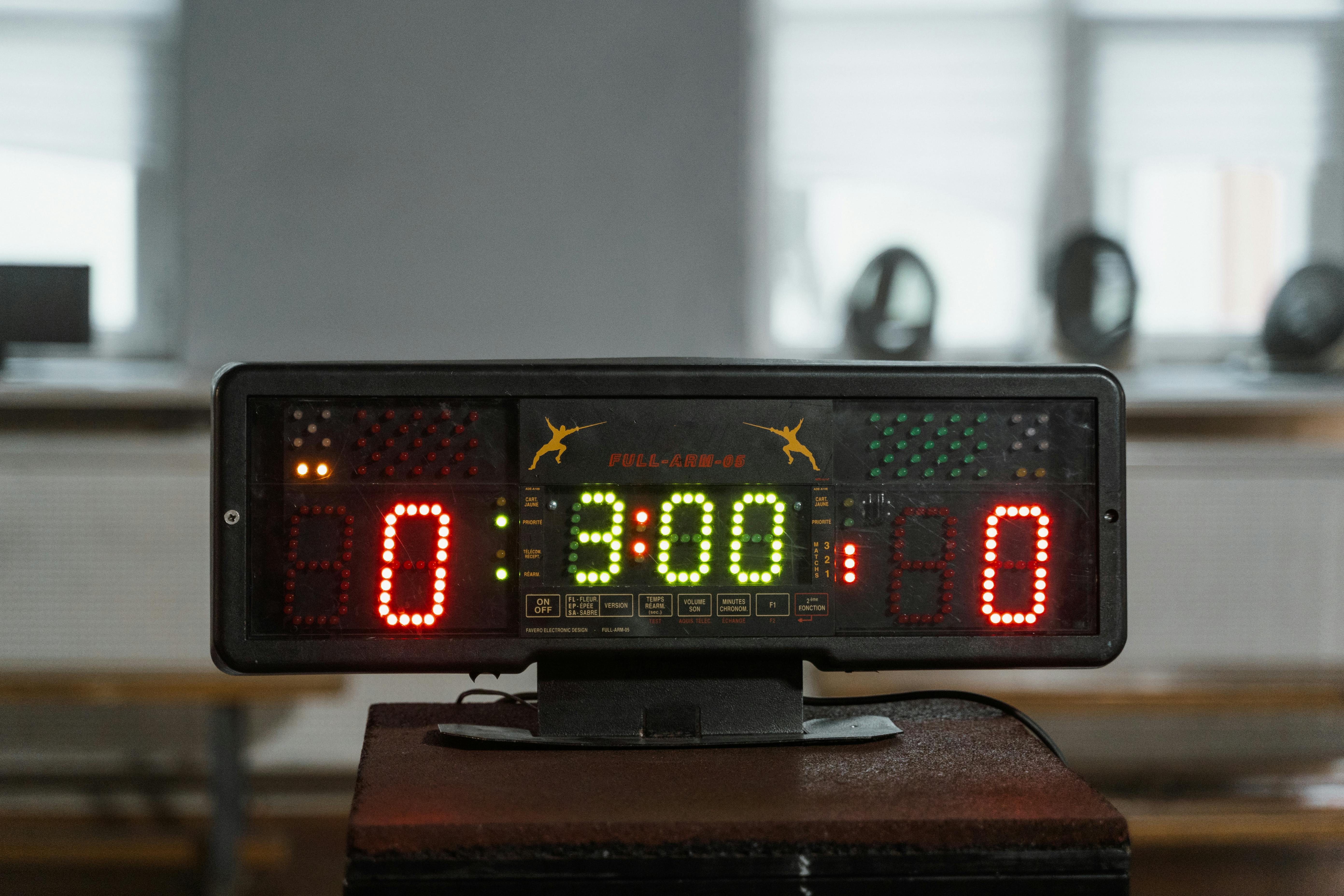 Marcador LED profesional mostrando resultado de partido de pádel con jugadores al fondo